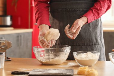 Makarna için hamur yapan adam mutfaktaki masada, yakın plan.