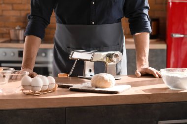 Mutfaktaki masada makarna makineli adam, yakın plan.