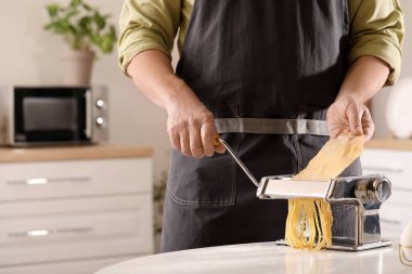 Adam mutfaktaki masada makineyle makarna yapıyor, yakın plan.