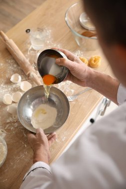 Erkek aşçı hamur işi yapıyor. Mutfaktaki masada, yakın plan.