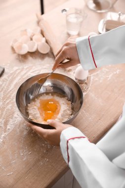 Mutfaktaki masada makarna için hamur yapan kadın aşçı, yakın plan.