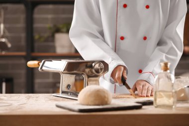 Mutfaktaki masada makineyle makarna yapan kadın aşçı, yakın plan.