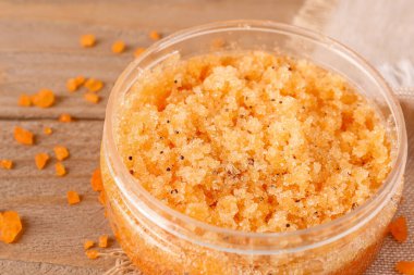 Tahta arka planda vücut fırçası ve deniz tuzu kavanozu, yakın plan.