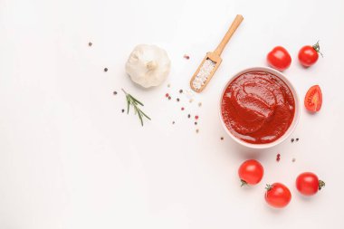 Beyaz arka planda bir kase lezzetli domates ezmesi, biber ve sarımsak.