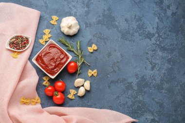 Lezzetli domates ezmesi, çiğ farfalle makarna ve mavi grunge arka planda biberiye karışımı.