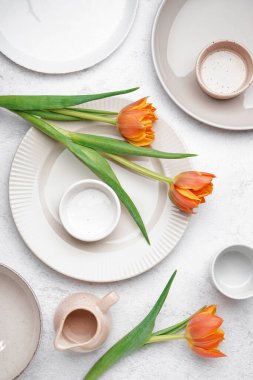 Beyaz grunge arka planda, temiz tabaklar ve güzel lale çiçekleriyle kompozisyon