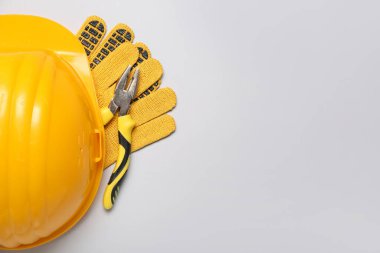 Gri arka planda sert şapka, kerpeten ve eldivenler