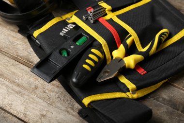 Kemerde pense ve ahşap masada aletler.