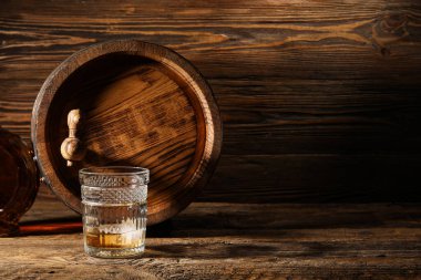 Bir bardak soğuk viski ve ahşap arka planda meşe fıçısı.
