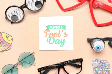 Kağıtlar APRIL FOOL 'S Day, bej arkaplanda balıklar ve gözlükler