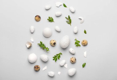 Gri arka planda Paskalya yumurtaları ve bitki yapraklarıyla yaratıcı kompozisyon