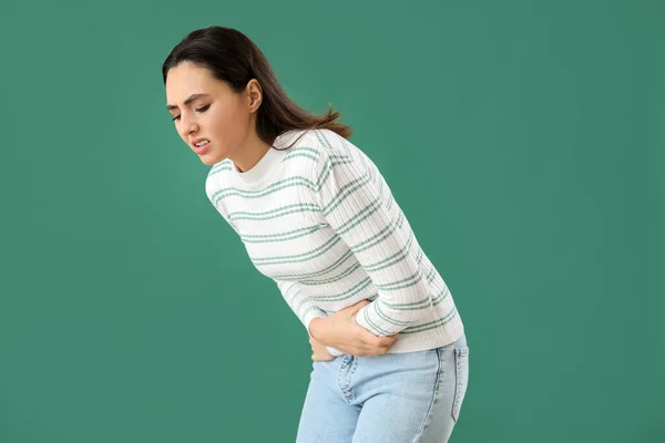 緑の背景に腹部の痛みを持つ若い女性 — ストック写真