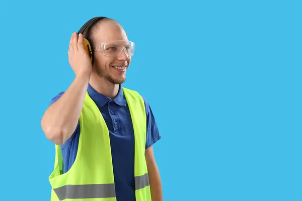 Mannelijke Werknemer Vest Met Beschermende Hoofdtelefoon Blauwe Achtergrond — Stockfoto