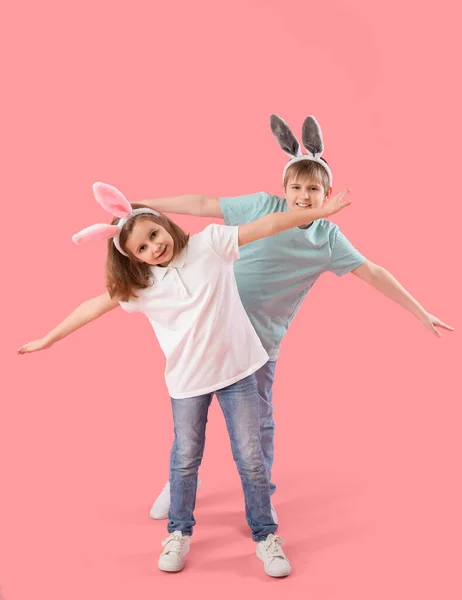 ピンクの背景にウサギの耳の小さな子供たち イースターのお祝い — ストック写真