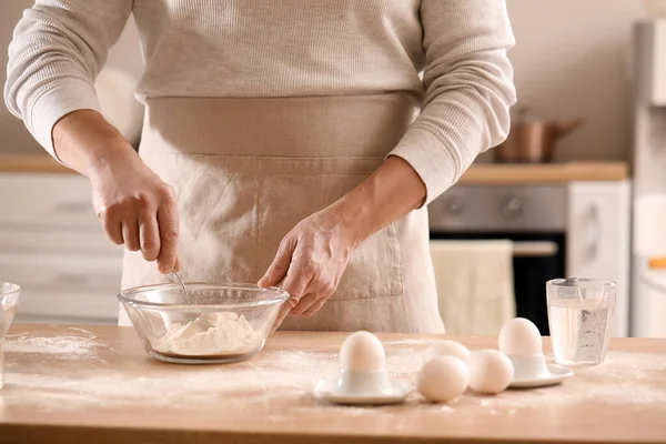 Erkek aşçı hamur işi yapıyor. Mutfaktaki masada, yakın plan.