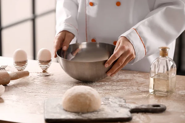 Mutfaktaki masada makarna için hamur yapan kadın aşçı, yakın plan.