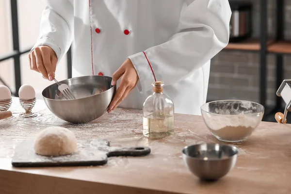 Mutfaktaki masada makarna için hamur yapan kadın aşçı, yakın plan.