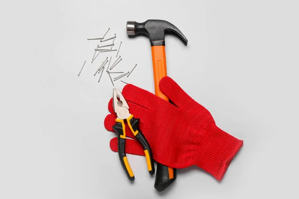 Stock image Pliers, glove, hammer and nails on grey background