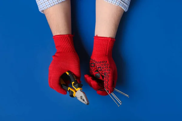 Male Hands Gloves Holding Pliers Nails Blue Background — Stock Photo, Image