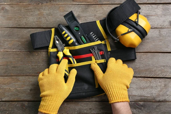 Männliche Hände Handschuhen Nehmen Werkzeug Aus Gürtel Auf Holztisch — Stockfoto