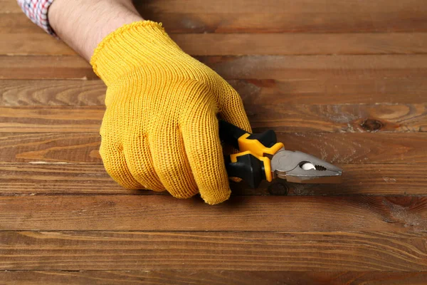 Männliche Hand Handschuhen Hält Zange Auf Holzgrund — Stockfoto