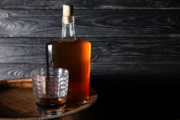 暗い木製の背景を背景に樽の上においしいウイスキーのガラスとボトル — ストック写真