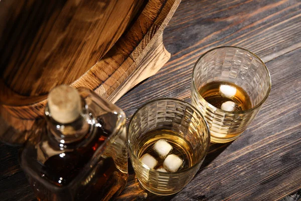暗い木製の背景に冷たいウイスキーのボトルとガラスとオーク樽 — ストック写真
