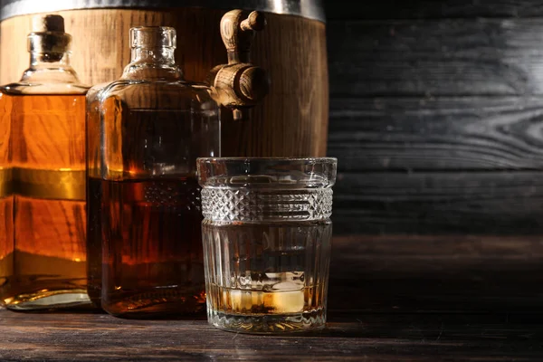 暗い木製の背景に冷たいウイスキーのボトルガラスとオーク樽 — ストック写真
