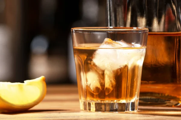 stock image Glass and bottle of tasty rum on table in bar, closeup