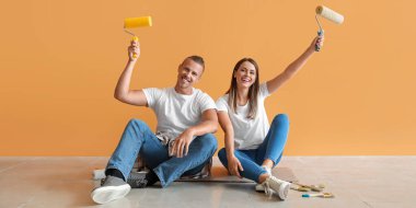 Yeni evlerinde yerde oturan boya silindirleri ile Mutlu genç çift