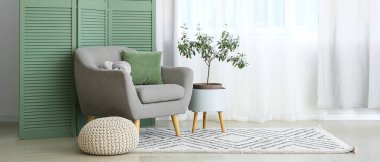 Gri koltuk, örülmüş puf ve açık salonda zeytin ağacı.