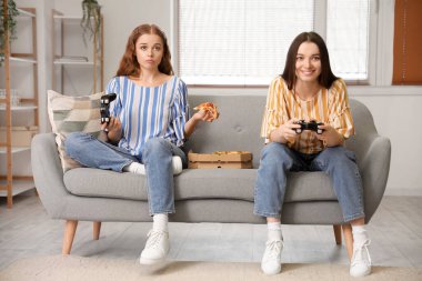 Lezzetli pizzalı genç kadınlar evde video oyunu oynuyorlar.