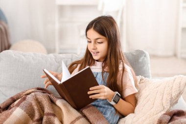 Evde akıllı akıllı kitap okuyan küçük kız.