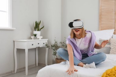 Pretty young woman in VR glasses in bedroom