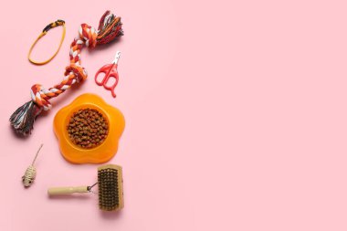 Hayvan bakımı aksesuarları ve pembe arka planda bir kase kuru yiyecek.