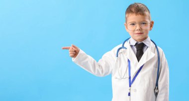 Küçük sevimli doktor mavi arka planda bir şeye işaret ediyor.
