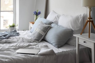 Ayna ve vazoda bahar çiçekleriyle aydınlık yatak odasının içinde.