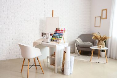 Interior of atelier with tailor's workplace, thread spools and easel