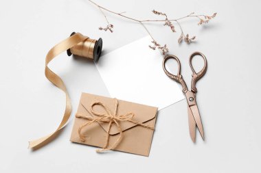 Beyaz arkaplanda boş kart, zarf, kurdele ve makas bileşimi