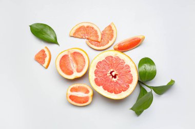 Açık arkaplanda olgun greyfurt ve bitki yapraklarıyla kompozisyon
