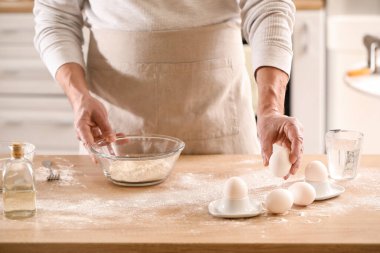 Erkek aşçı hamur işi yapıyor. Mutfaktaki masada, yakın plan.