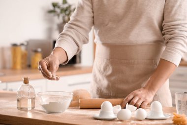 Erkek aşçı hamur işi yapıyor. Mutfaktaki masada, yakın plan.