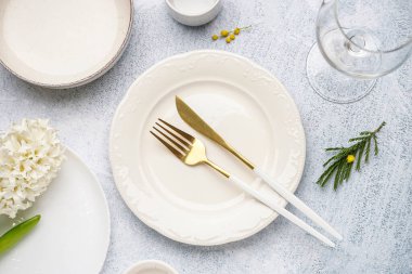 Temiz tabaklar, çatal bıçak takımı ve gri arkaplanda güzel çiçekler.
