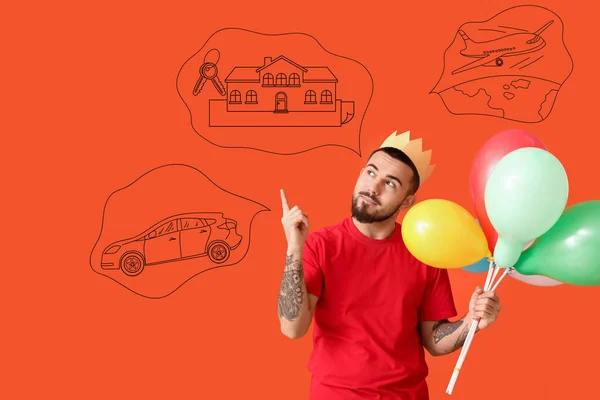 Happy man with birthday balloons making wishes on red background