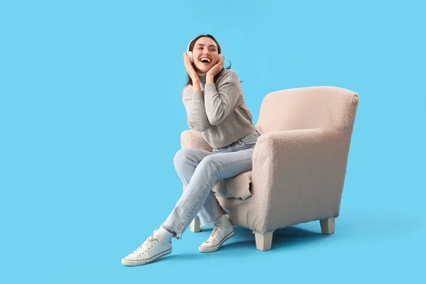 Νεαρή Γυναίκα Ακουστικά Κάθεται Μαλακή Πολυθρόνα Μπλε Φόντο — Φωτογραφία Αρχείου