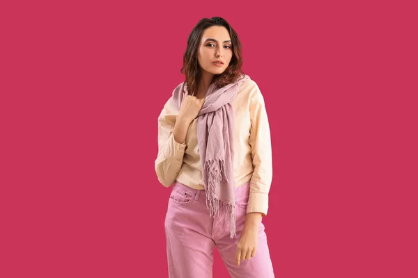 Stylish young woman in scarf on pink background