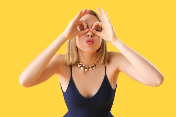 Funny young woman with necklace on yellow background