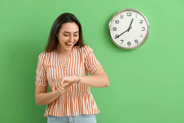 時計と緑の壁の近くに腕時計を見て若い女性 — ストック写真