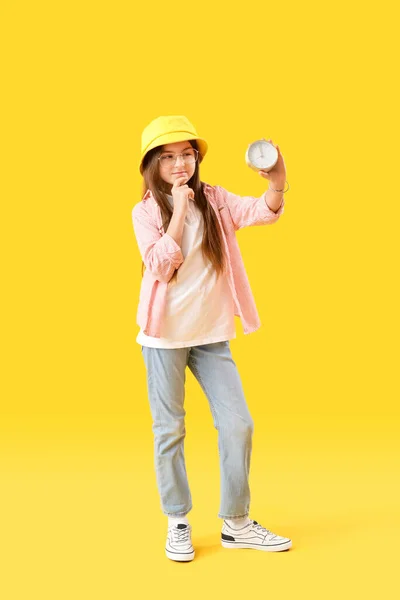 Sarı Arka Planda Çalar Saati Olan Düşünceli Küçük Kız — Stok fotoğraf