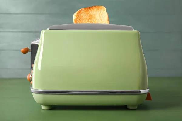 现代烤面包机 绿色木制桌子上有脆面包片 — 图库照片
